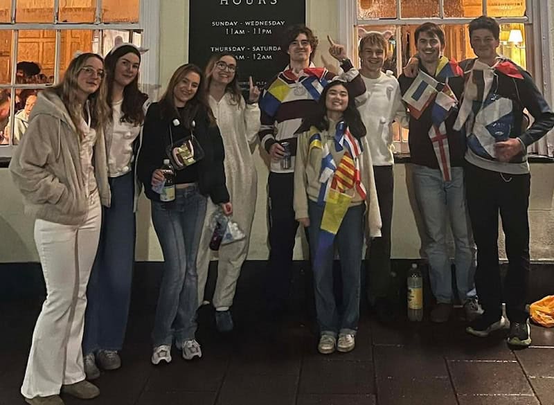 The Cambridge teams dressed up with flags for the 2025 Oxford Magnum social, standing outside the Lamb and Flag pub in Oxford